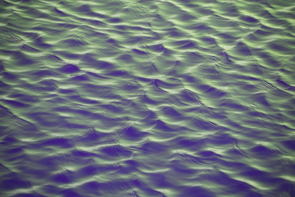 Abstract wallpaper with green and purple water waves and ripples creating a calming background