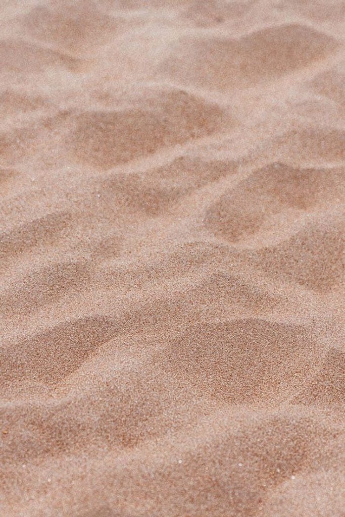 Macro photo of rippled tan sand dunes with soft light highlighting natural texture background Wallpaper