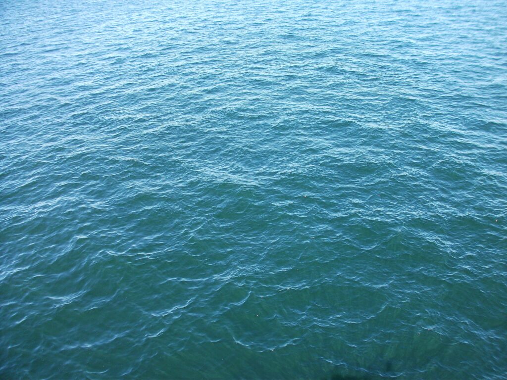 Realistic rippling sea water texture in blue and green natural light ocean surface background Wallpaper