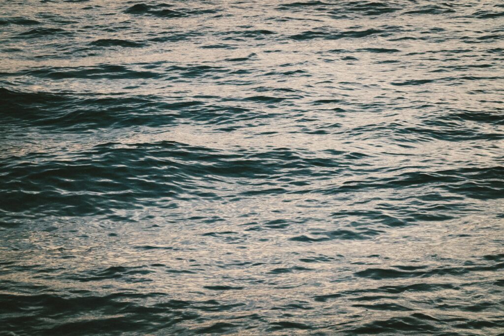 Calming deep blue and green sea surface with soft natural light reflections wallpaper background