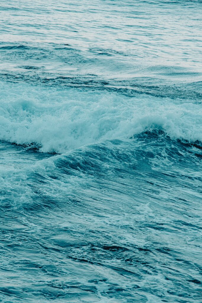 Ocean waves crashing with vibrant blue tones and white sea foam in a calming wallpaper background