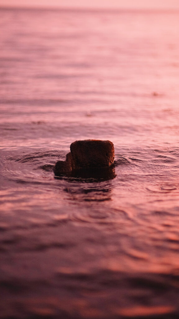 Calming serene wallpaper with gentle water ripples around stone warm pink hues tranquil surface