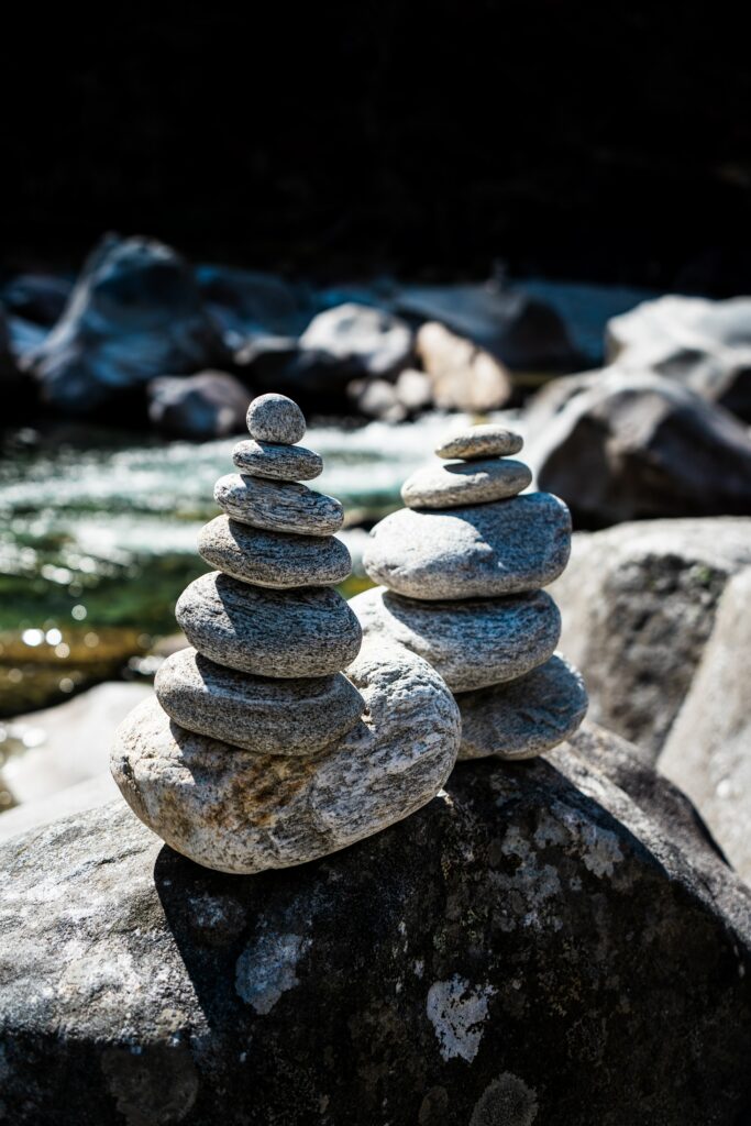 Smooth river stones stacked on boulder by water edge sunlight highlights natural textures wallpaper