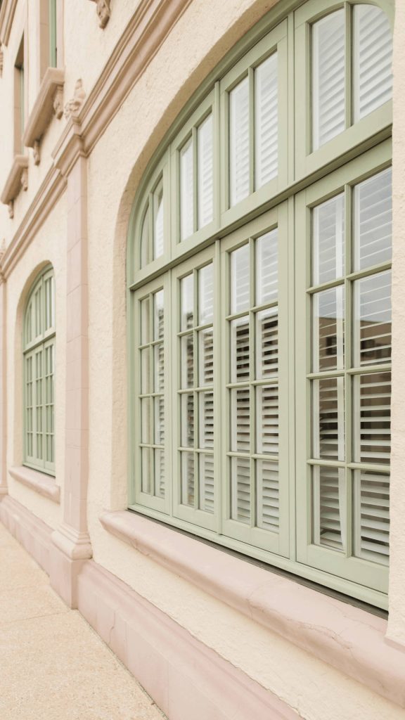 Arched window with sage green frame on beige stucco wall minimalist calming wallpaper background