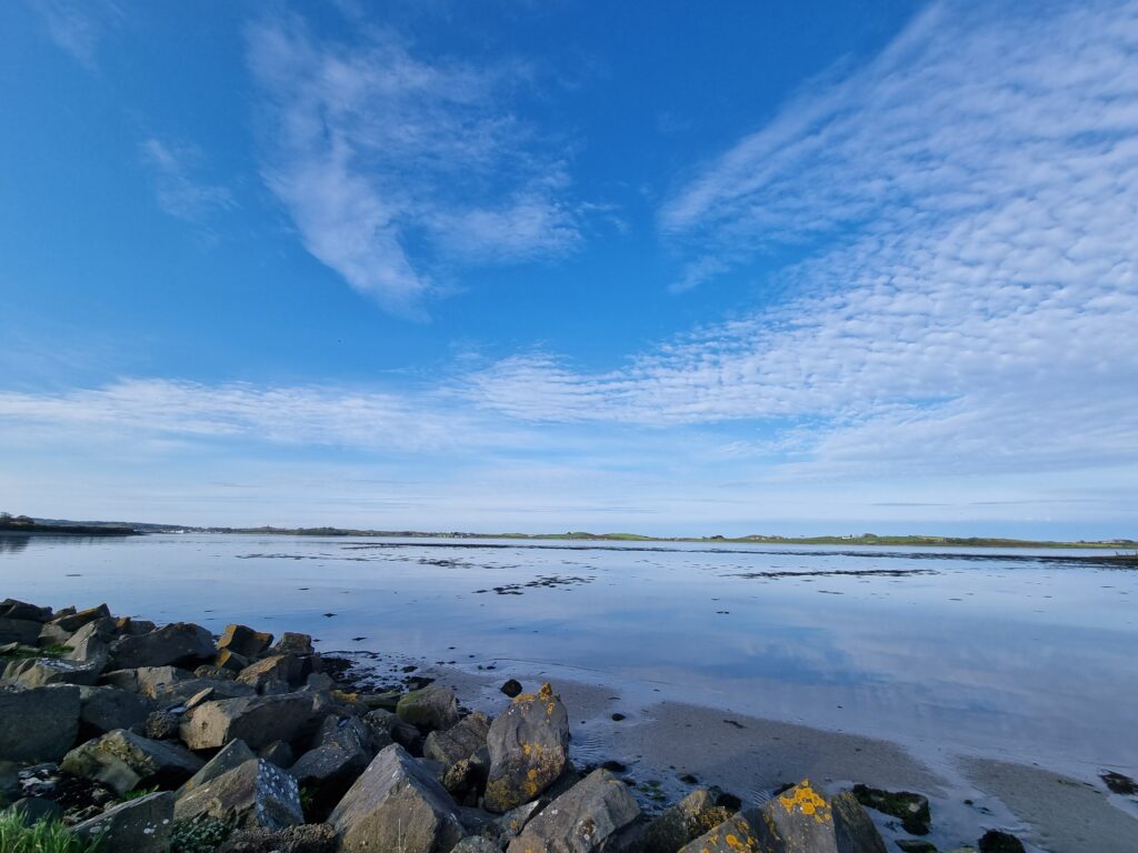 Serene seascape with large stones shore tranquil sea horizon scattered clouds soft daylight Wallpaper