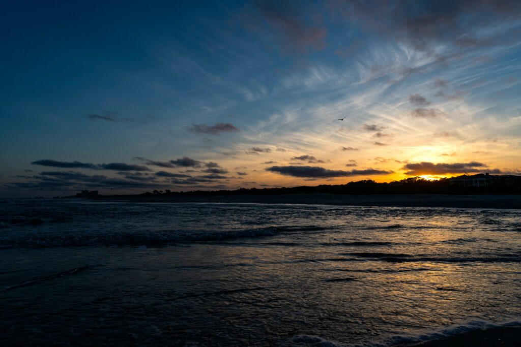 Sunset over tranquil sea with golden blue waves and wispy clouds coastal wallpaper background