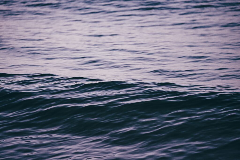 Calming sea waves at twilight with deep blue and violet ripples peaceful wallpaper background