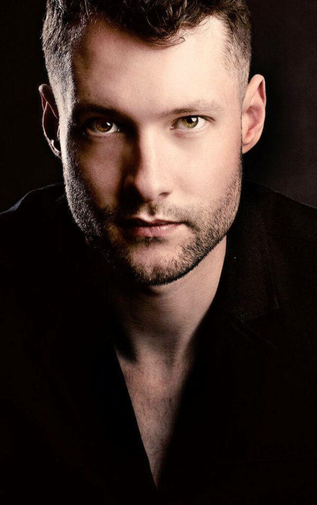 Close-up portrait of Calum Scott with dramatic lighting and intense gaze on dark background wallpaper
