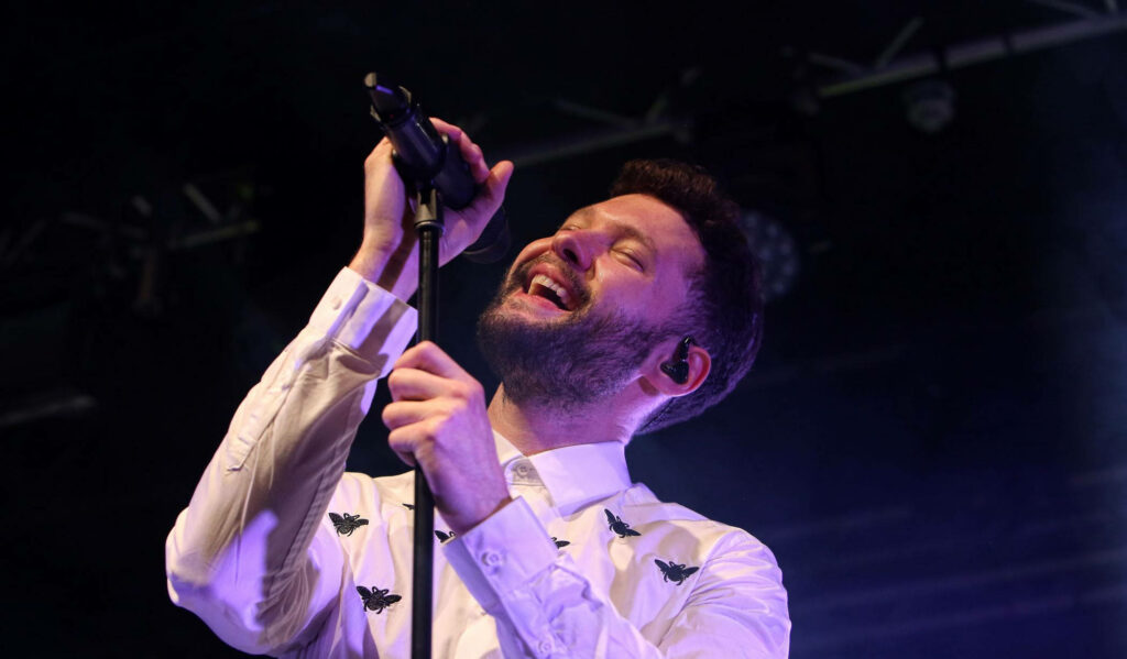 Calum Scott passionately singing live at Rock City vibrant stage lighting close-up concert energy Wallpaper