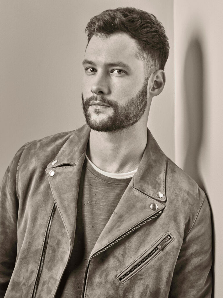 Calum Scott monochrome portrait with confident stare and stylish suede jacket wallpaper background