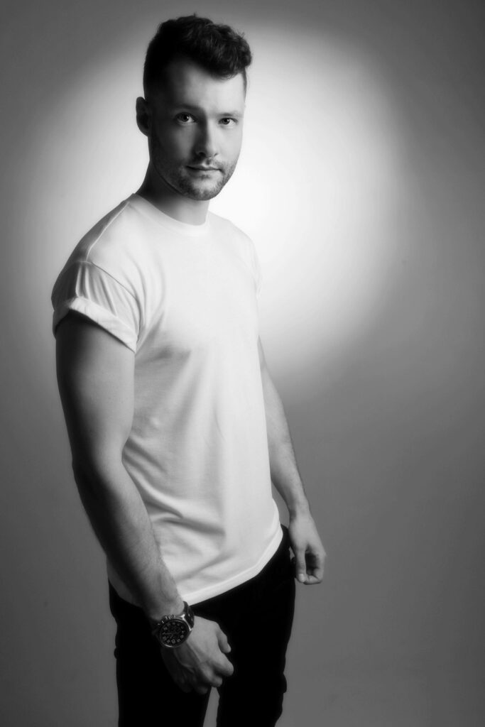 Greyscale portrait of Calum Scott in minimalist style with soft lighting and textured white shirt Wallpaper