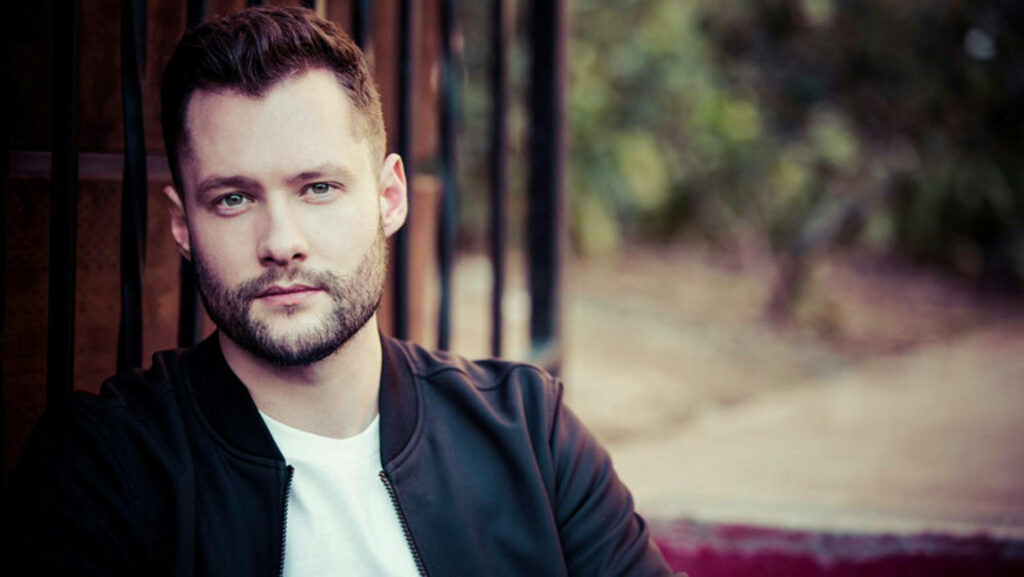 Calum Scott candid outdoor wallpaper with soft natural light and muted earth tones focus