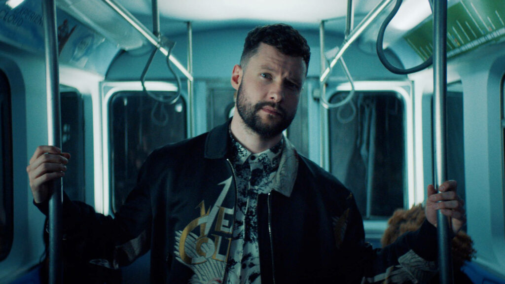Calum Scott in blue-lit subway wearing patterned shirt and black jacket with moody lighting Wallpaper