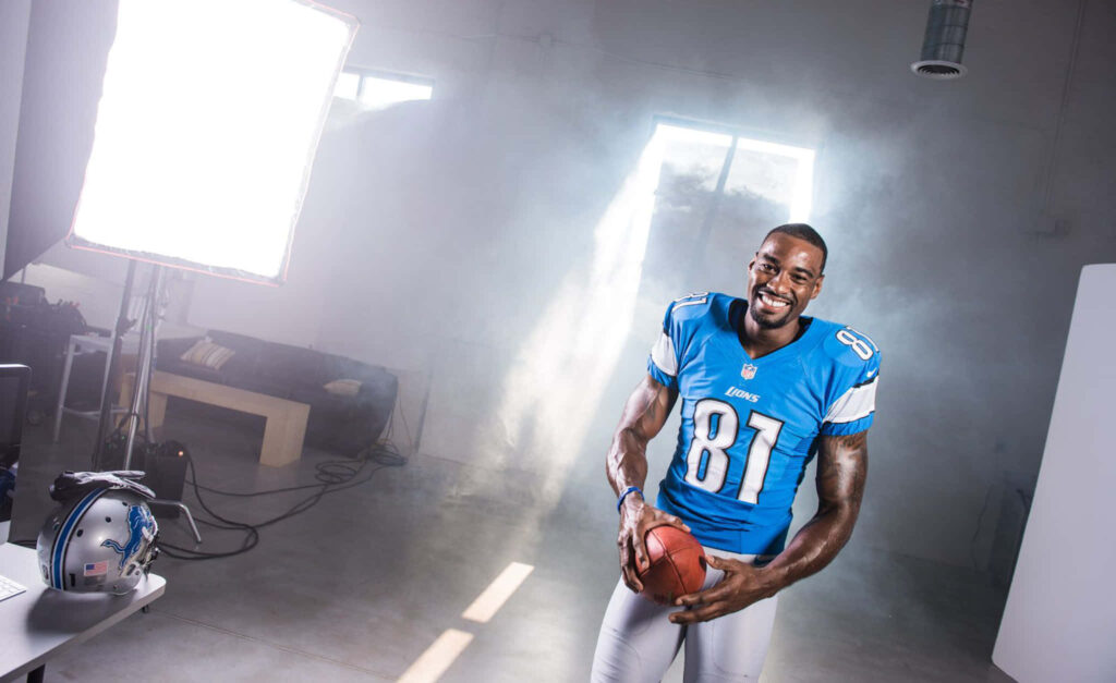 Calvin Johnson Detroit Lions wide receiver holding football smiling confident NFL legend wallpaper