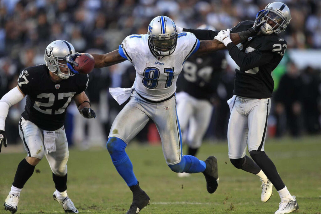 Calvin Johnson Detroit Lions number 81 breaking away from defenders in vibrant football action Wallpaper