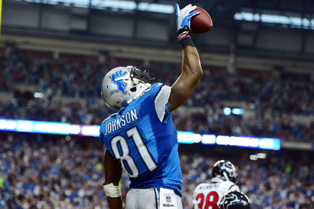 Calvin Johnson Detroit Lions leaping one-handed catch in blue silver uniform stadium background Wallpaper