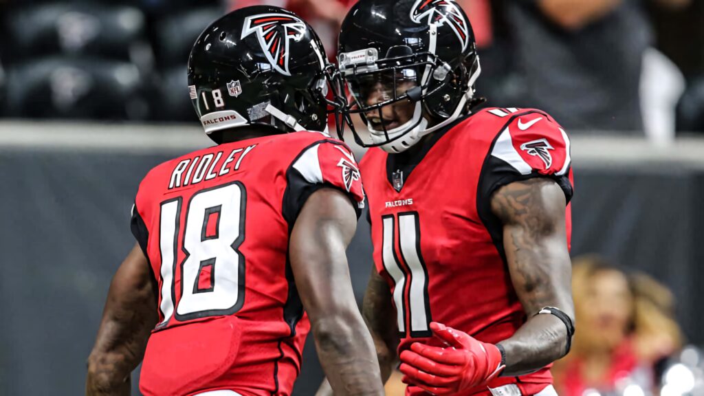 Calvin Ridley and teammate celebrate in vibrant Atlanta Falcons red uniforms on football field Wallpaper