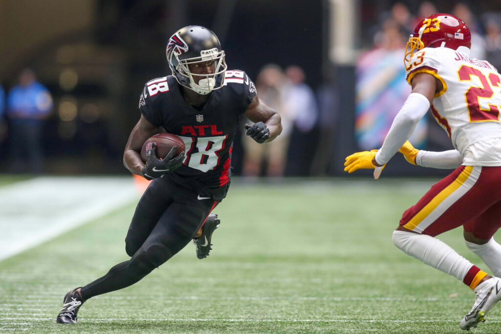 Calvin Ridley sprinting in Atlanta Falcons uniform evading defender during intense NFL game action Wallpaper