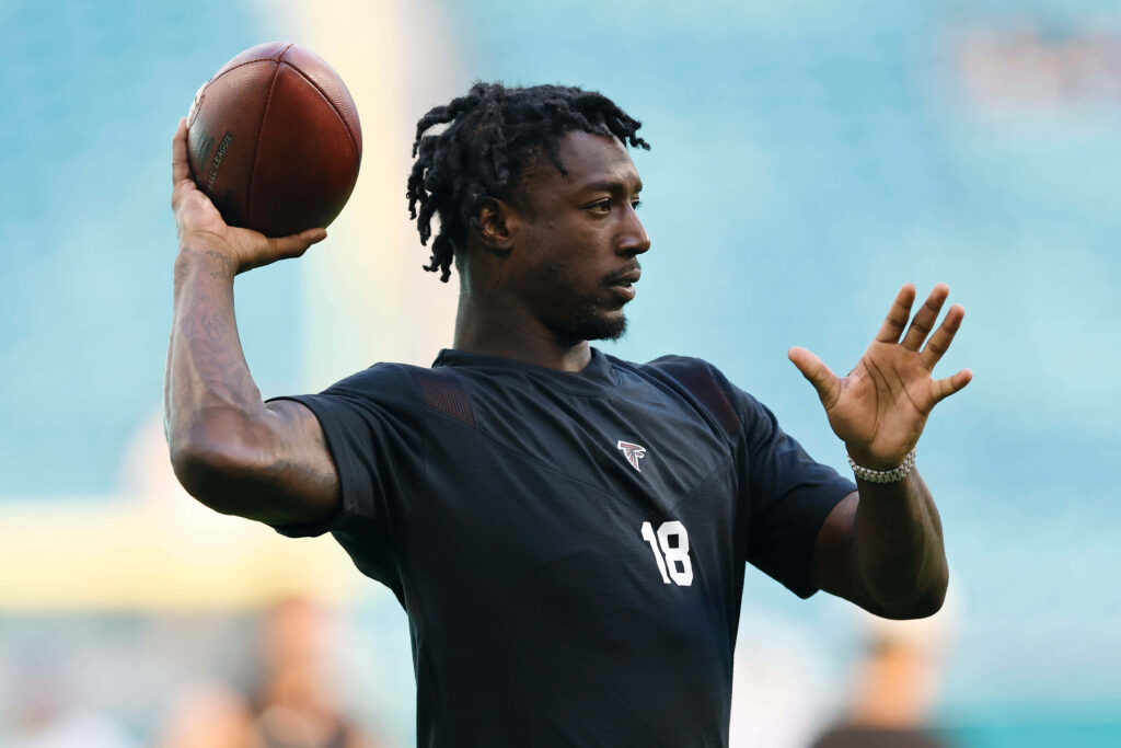 Calvin Ridley warming up in black practice shirt holding football at bright stadium practice Wallpaper