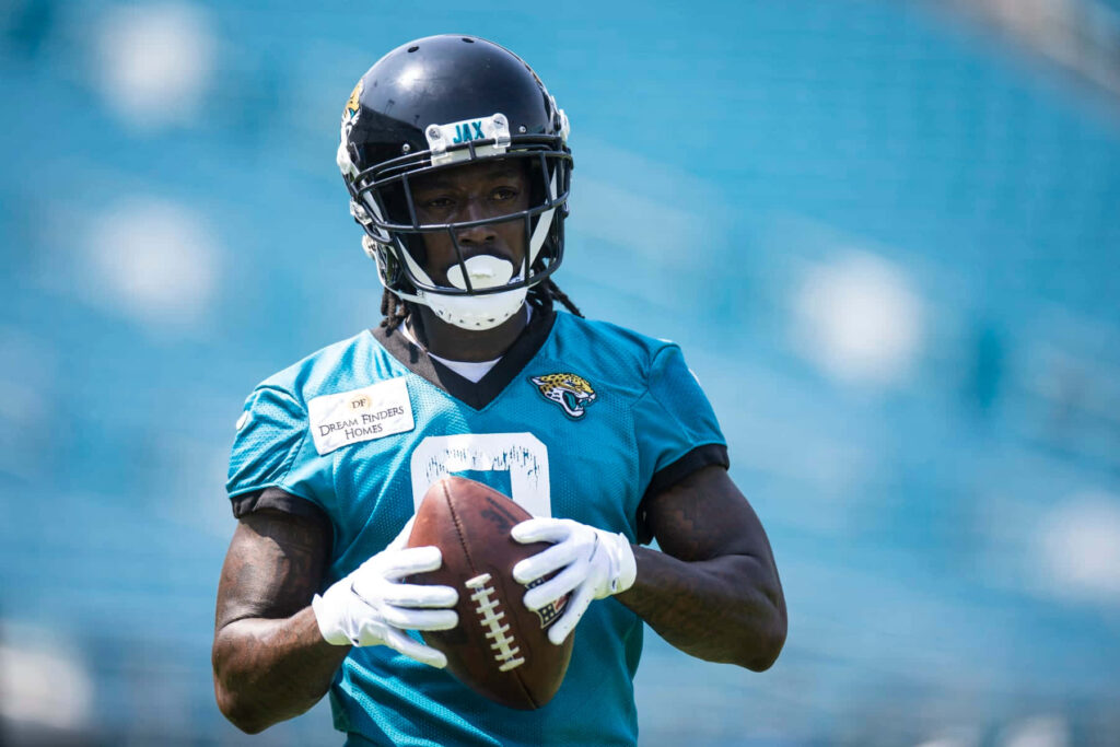Calvin Ridley focused in Jaguars teal jersey holding football during intense training in stadium Wallpaper