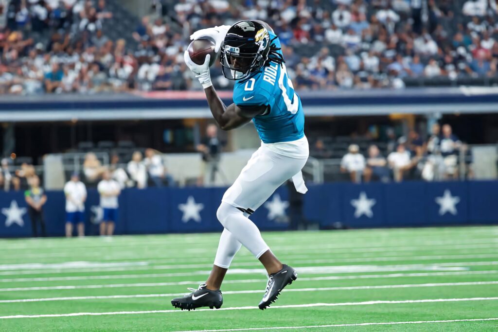 Calvin Ridley leaps to catch football in teal Jaguars jersey with vibrant stadium crowd background Wallpaper