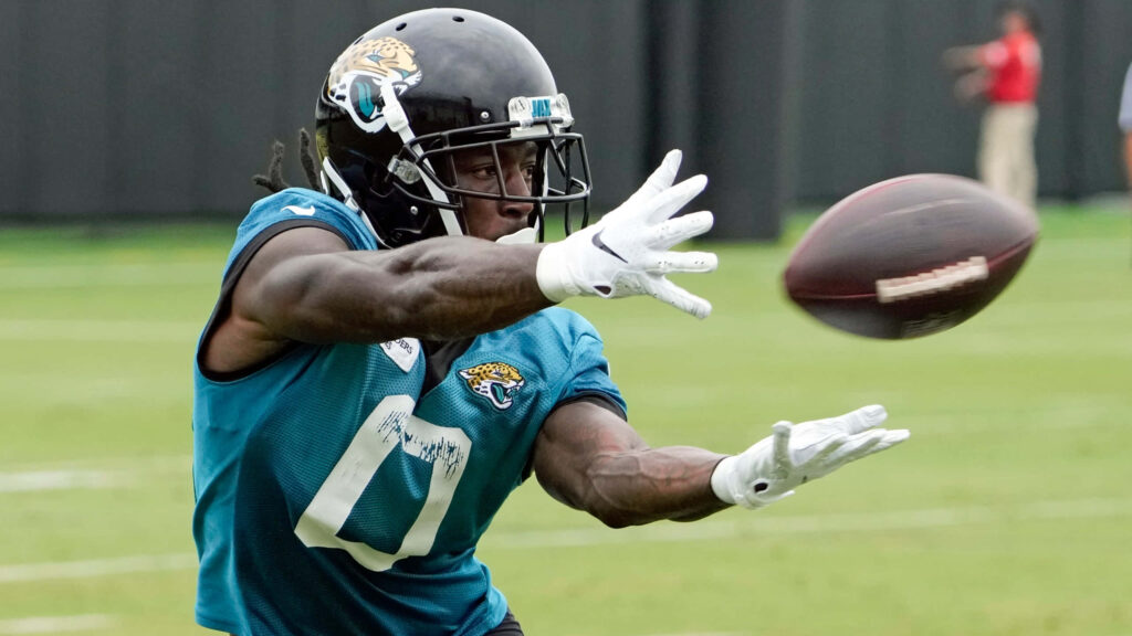 Calvin Ridley catching football in Jaguars teal jersey during intense practice on green field Wallpaper