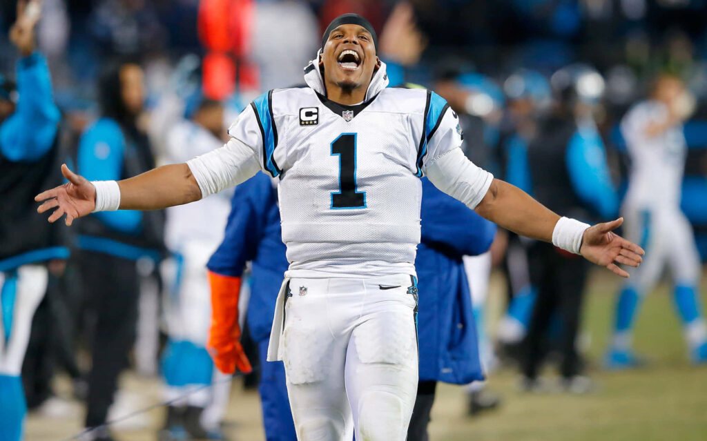 Cam Newton smiling in Carolina Panthers uniform showing energy and leadership on football field Wallpaper