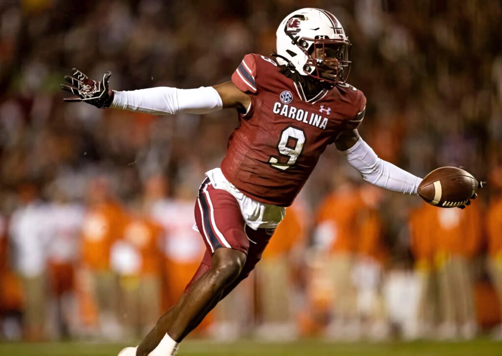 Football player Cam Smith in Carolina uniform running with ball under stadium lights wallpaper