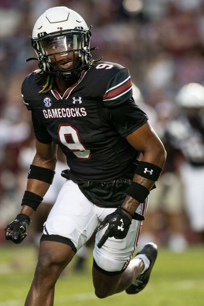 Gamecocks football player Cam Smith number nine in black uniform in dynamic action on field Wallpaper