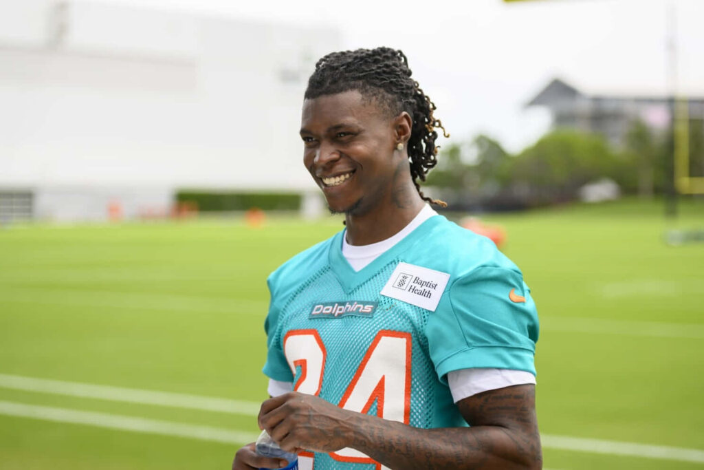 Cam Smith smiling in teal Miami Dolphins jersey 24 on football field bright outdoor wallpaper