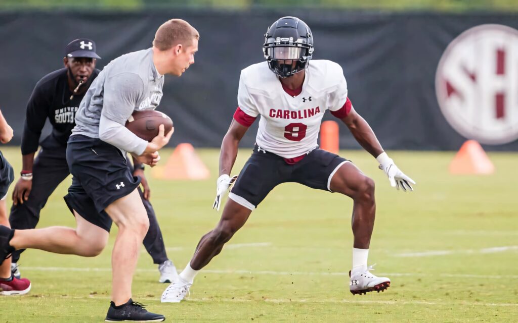 Cam Smith number 9 focused during Carolina football practice drill on green field with teammates Wallpaper