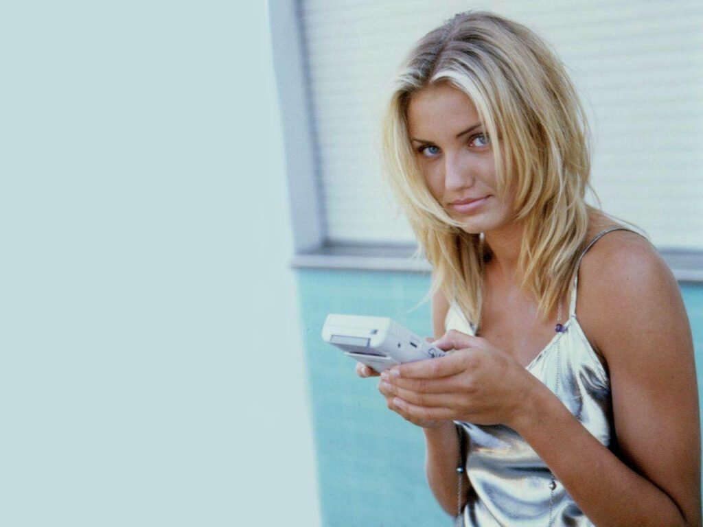 Cameron Diaz on phone call holding white smartphone against soft blue modern background wallpaper