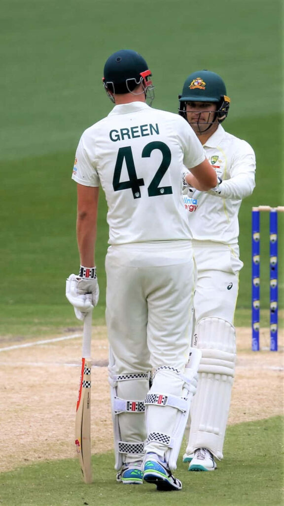 Cameron Green in white Australian Test cricket uniform sharing a focused moment on pitch Wallpaper