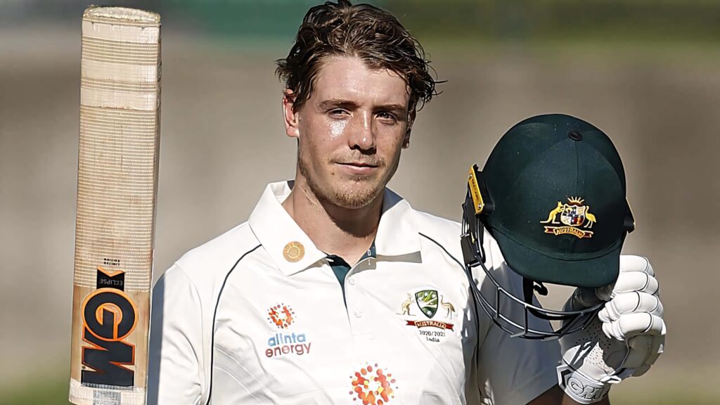 Cameron Green in Australian cricket whites holding bat and helmet with blurred background Wallpaper