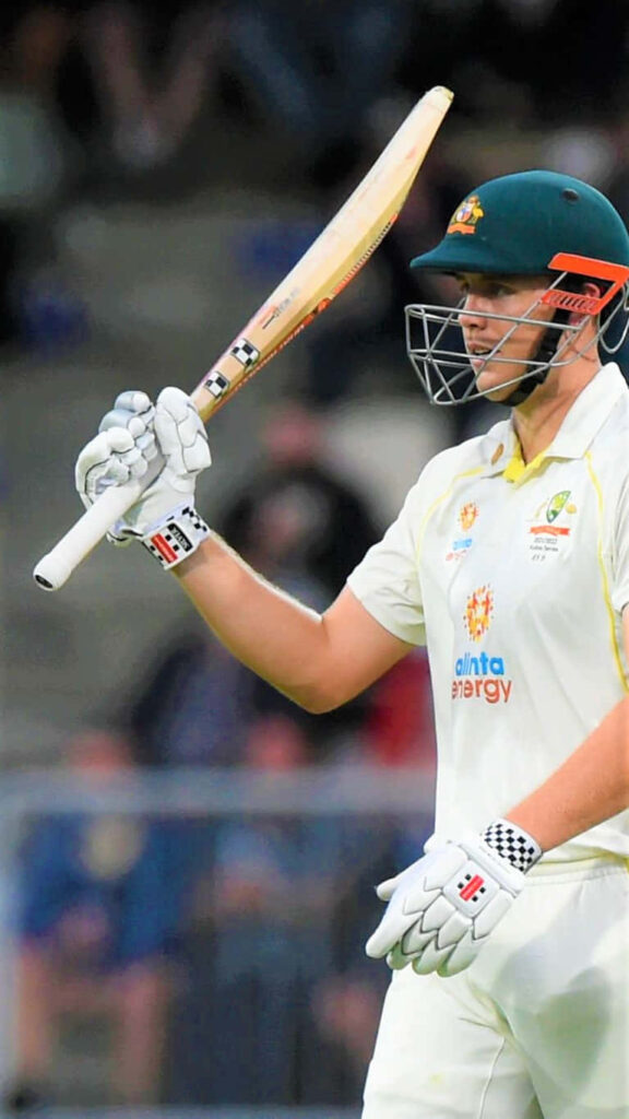Cameron Green in Australian Test cricket uniform celebrating with bat raised under stadium lights Wallpaper