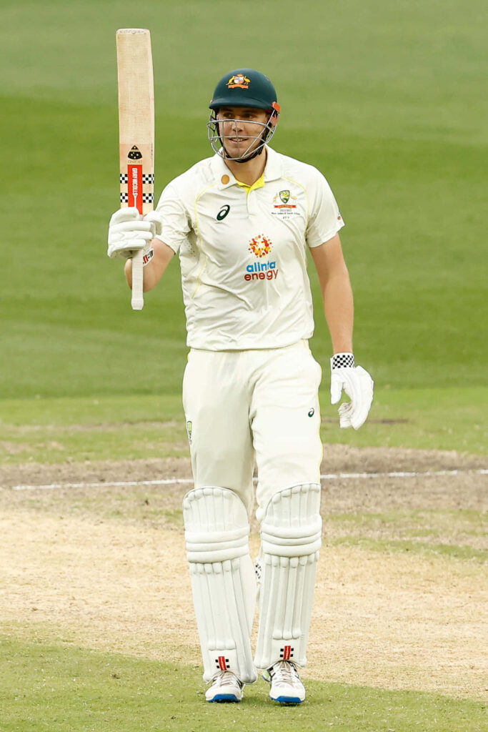 Cameron Green celebrates on field in white test cricket kit against vibrant green background Wallpaper