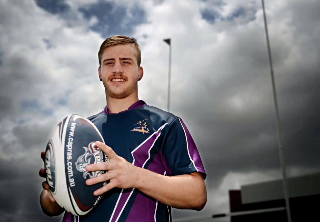 Cameron Munster in Melbourne Storm jersey holding rugby ball under dramatic cloudy sky wallpaper