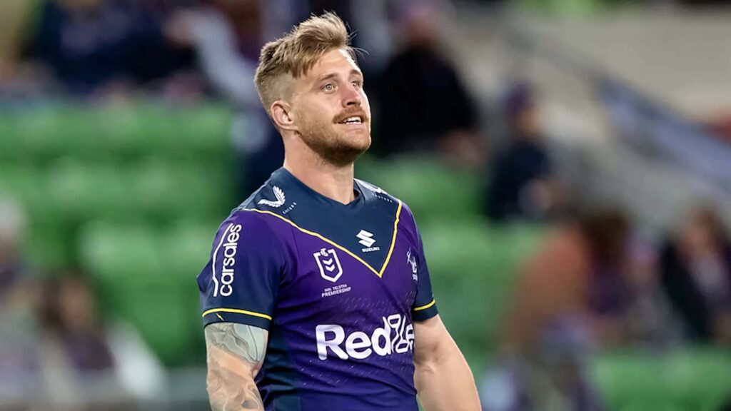Cameron Munster in purple Melbourne Storm jersey on vibrant stadium field focused rugby league star Wallpaper