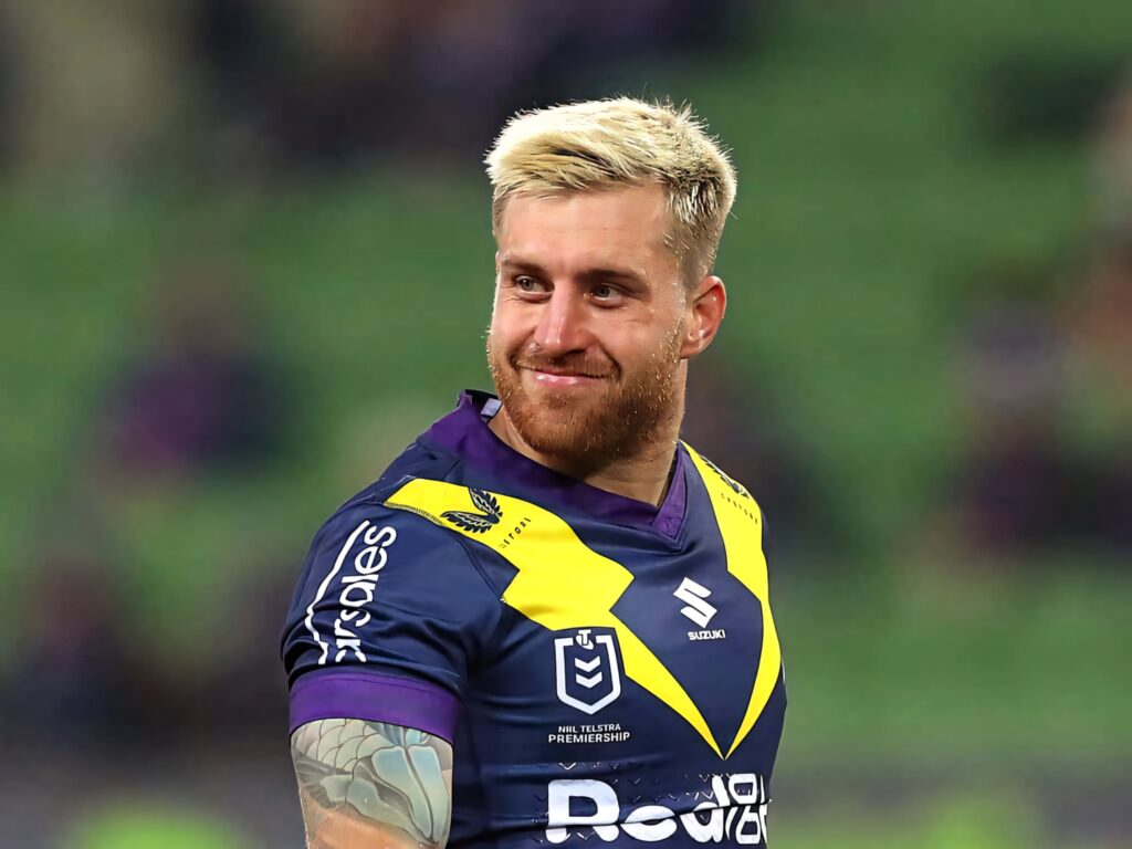 Cameron Munster in Melbourne Storm jersey dynamic pose vibrant NRL wallpaper stadium background