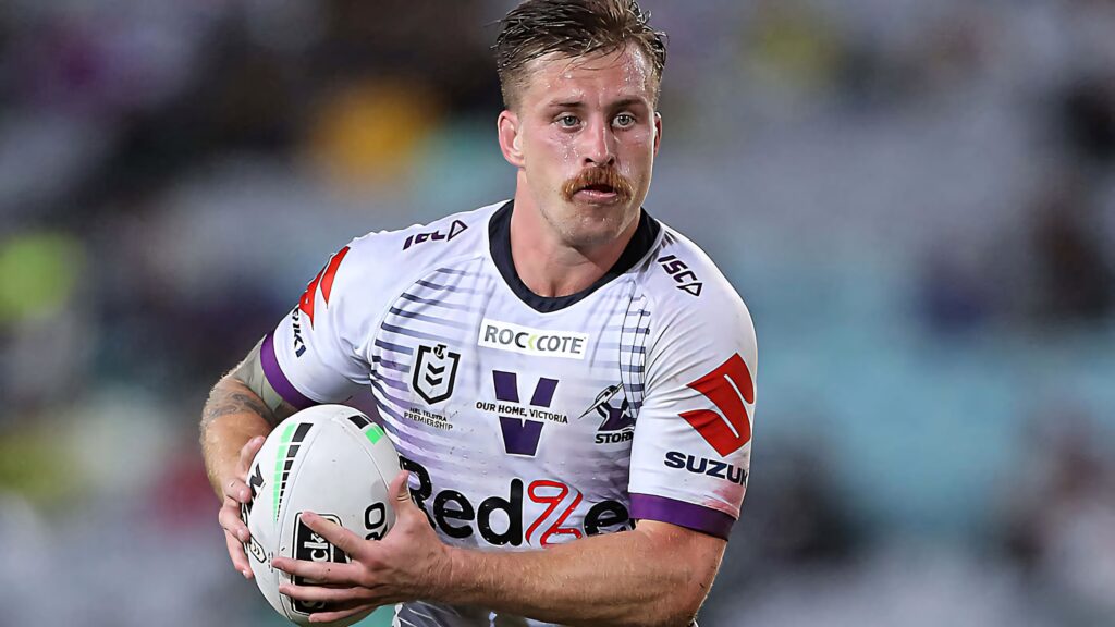 Cameron Munster Melbourne Storm rugby league player in white purple jersey holding ball in action Wallpaper