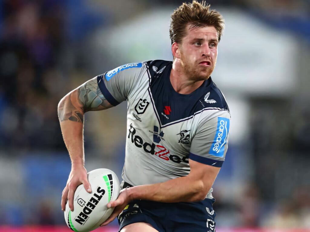 Cameron Munster Melbourne Storm rugby player gripping ball intense action stadium background Wallpaper