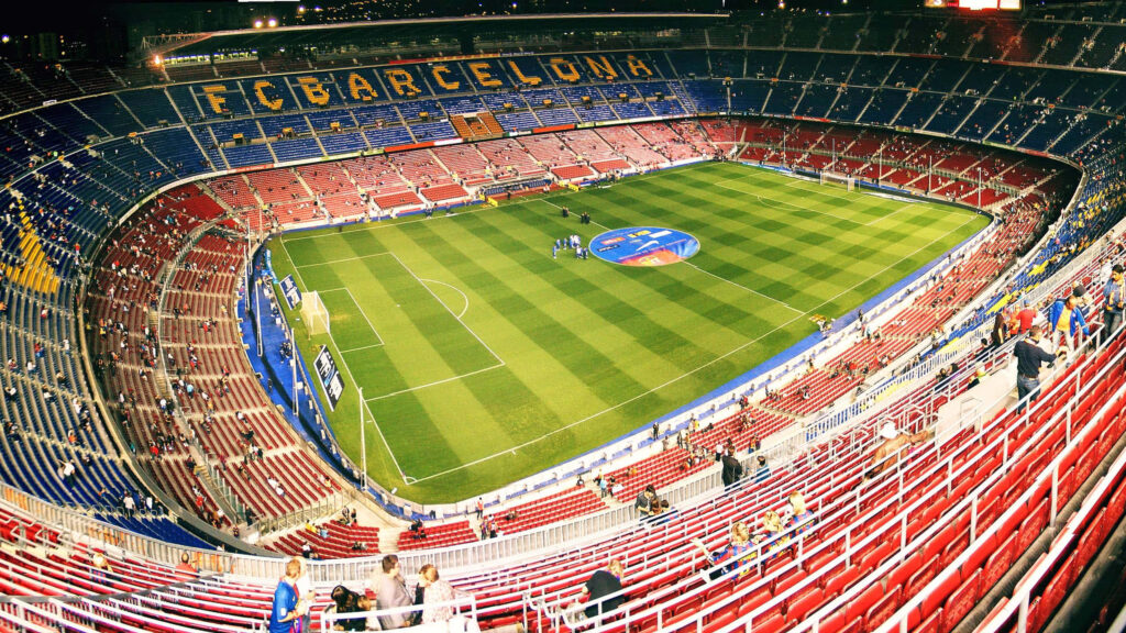 Evening view of Camp Nou Stadium with FC Barcelona seats lush green pitch and warm lights Wallpaper