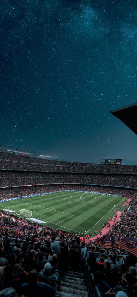Camp Nou stadium lit under starry night sky during thrilling football match with vibrant crowd Wallpaper