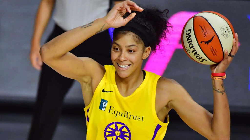 Candace Parker in vibrant yellow uniform confidently holding basketball on court with dynamic focus Wallpaper