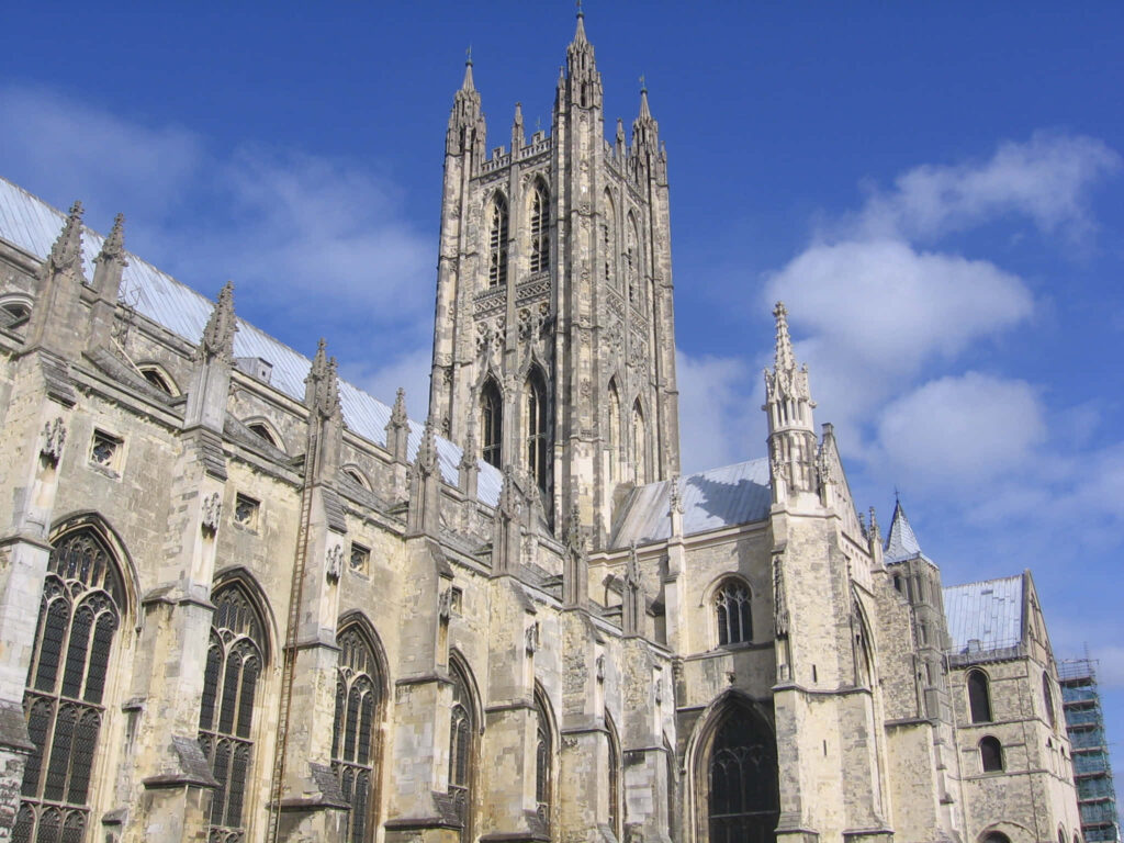 Canterbury Cathedral Gothic exterior with towering spires and intricate stonework under blue sky Wallpaper