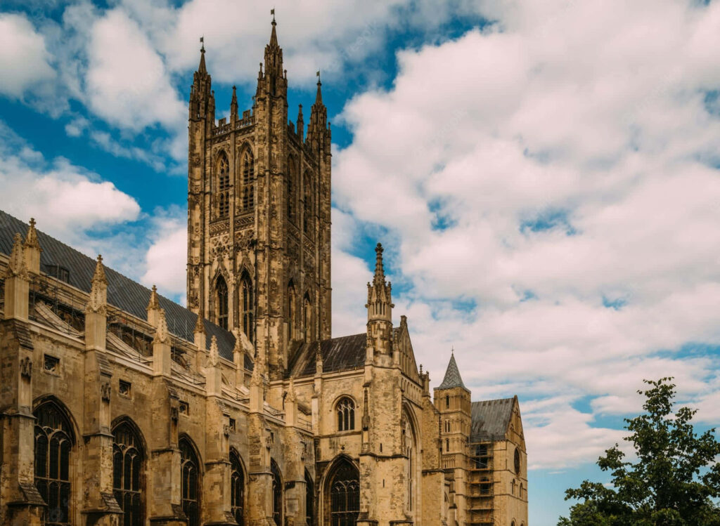 North side of Canterbury Cathedral Gothic architecture tall towers and detailed stonework under blue sky Wallpaper