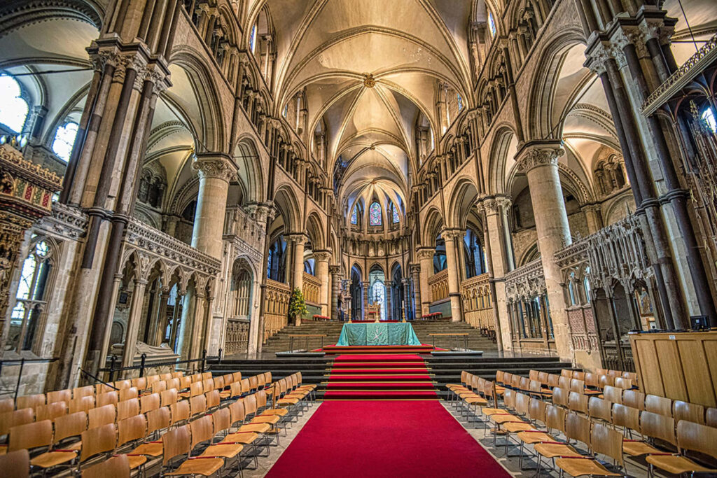 Canterbury Cathedral quire with red carpet vaulted ceilings Gothic arches and columns in warm light Wallpaper