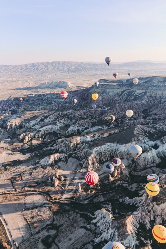 Aerial view of Cappadocia and Goreme with colorful hot air balloons over rocky landscapes at sunrise Wallpaper