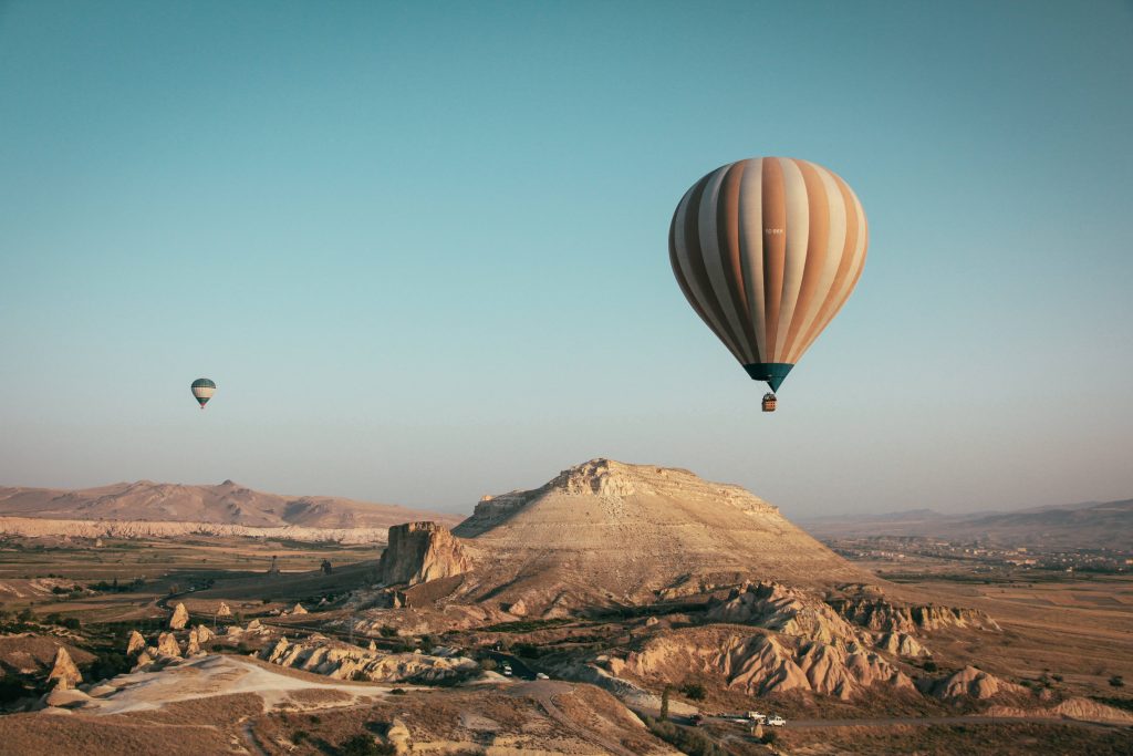Hot air balloon drifting over Cappadocia rock formations at sunrise serene landscape wallpaper