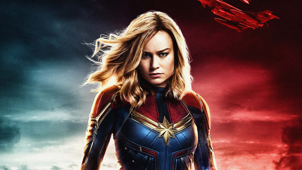 Captain Marvel Brie Larson in iconic superhero costume with dynamic red and blue background wallpaper
